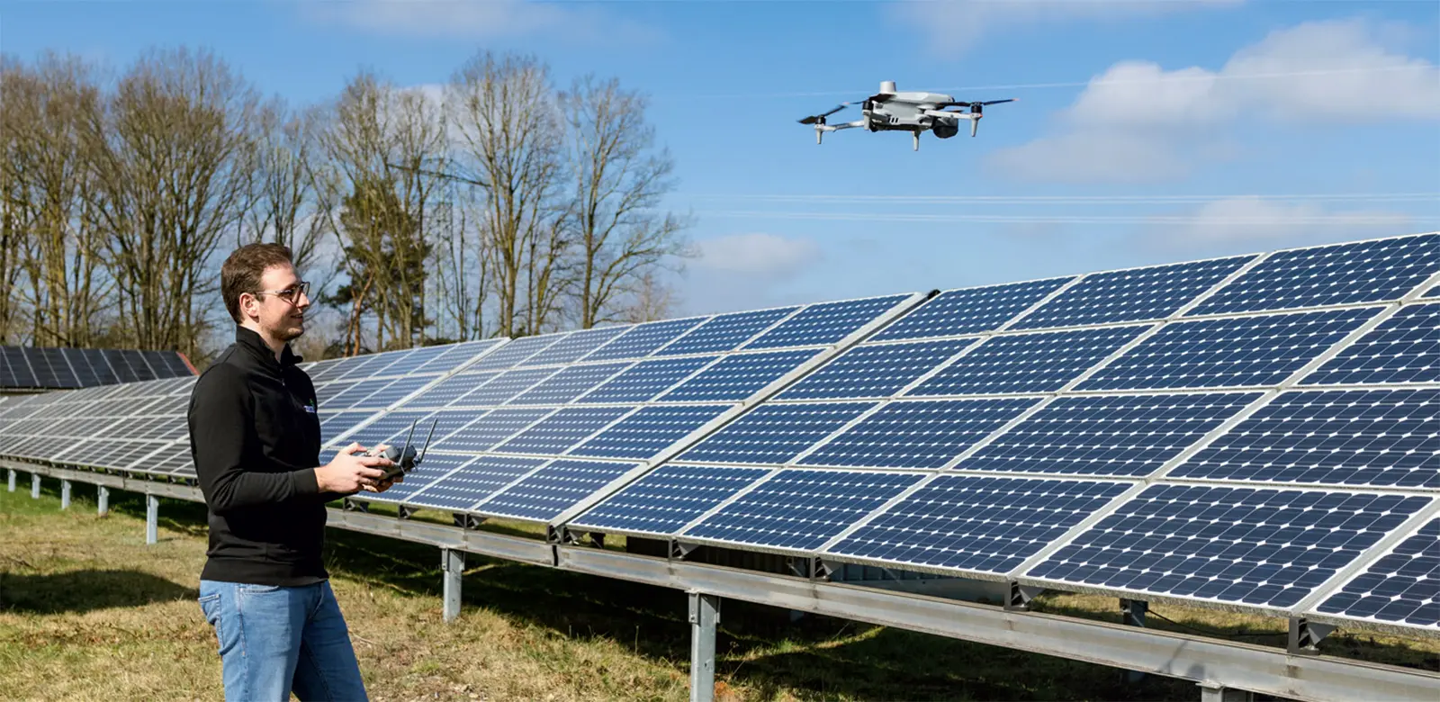 Luftaufnahme von mehreren Solarpanelen in Reihen auf einem landwirtschaftlichen Feld mit grünen Pflanzen